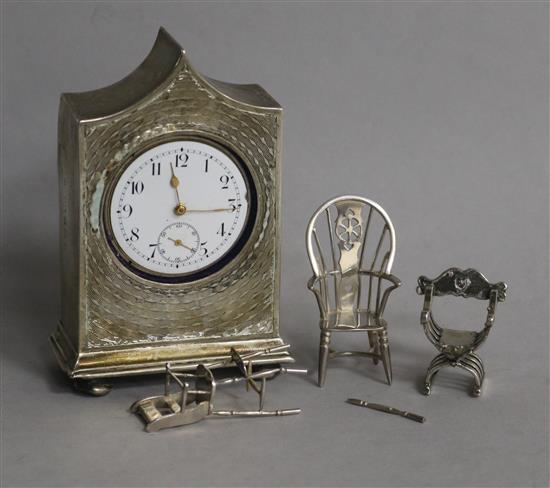 Three miniature silver chairs and a silver mantel timepiece.